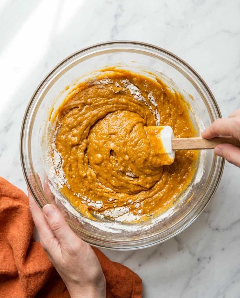 هم‌ زدن خمیر طلایی و خامه‌ ای کیک در کاسه شیشه‌ ای